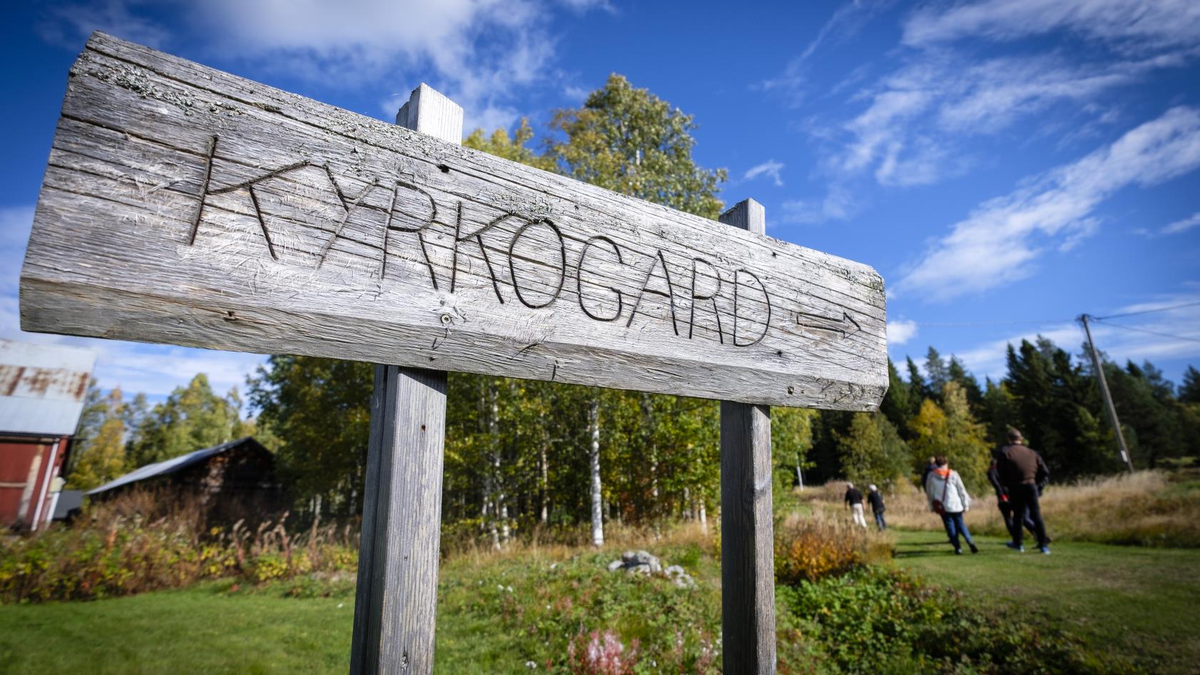 En hemmasnickrad träskylt talar om att en kyrkogård ligger längre fram längs stigen.