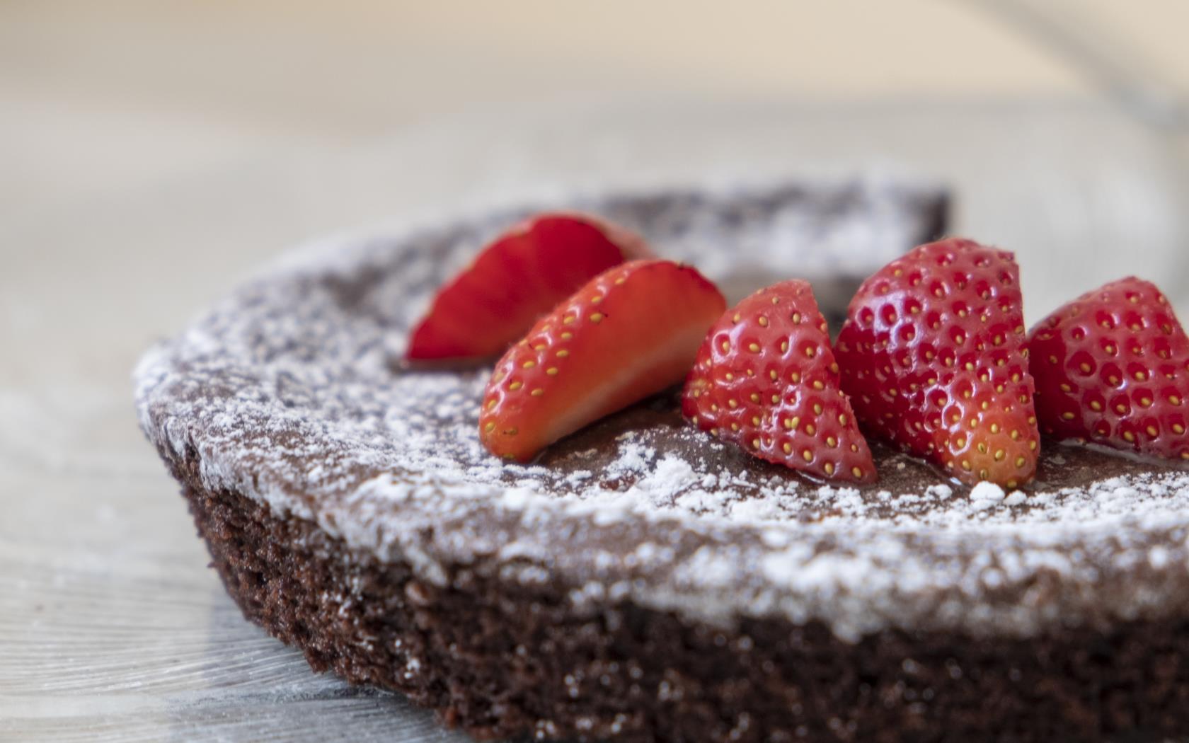 En kladdkaka toppad med florsocker och jordgubbar.