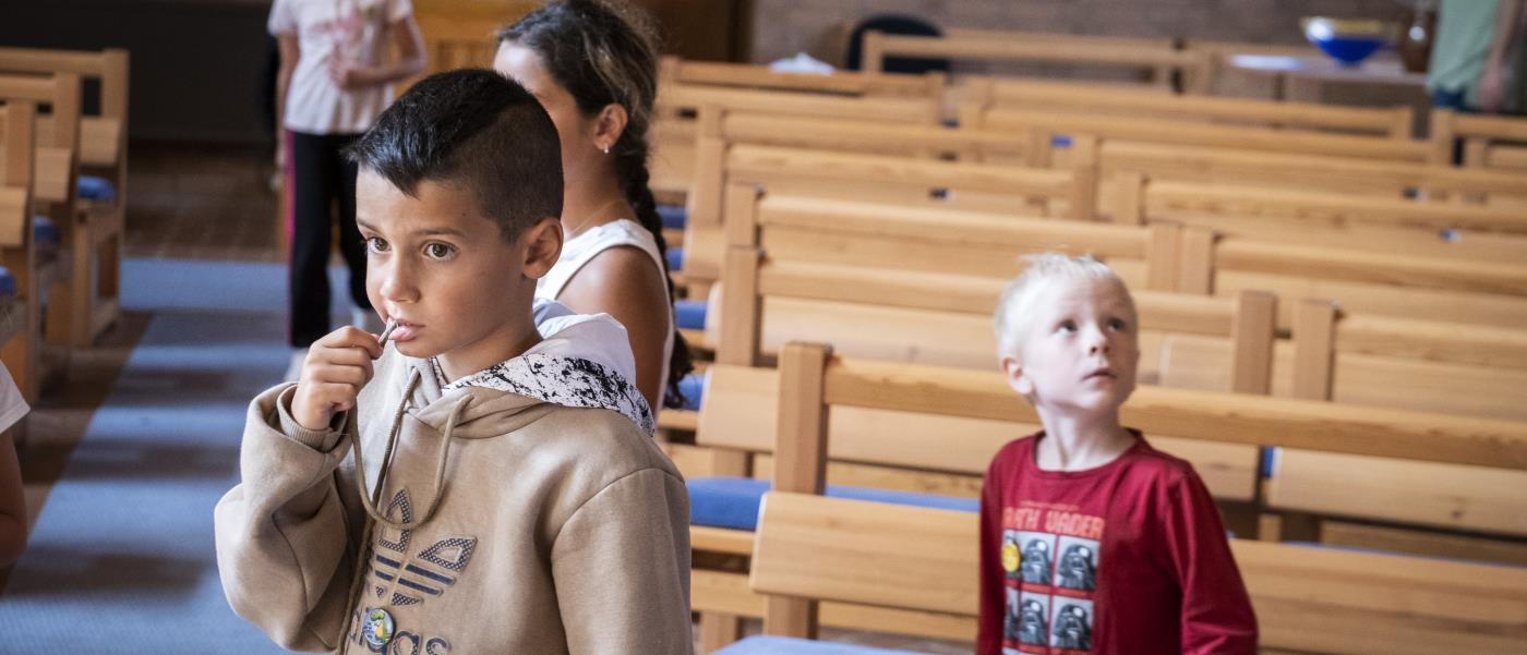 Några barn står utspridda i en kyrka.