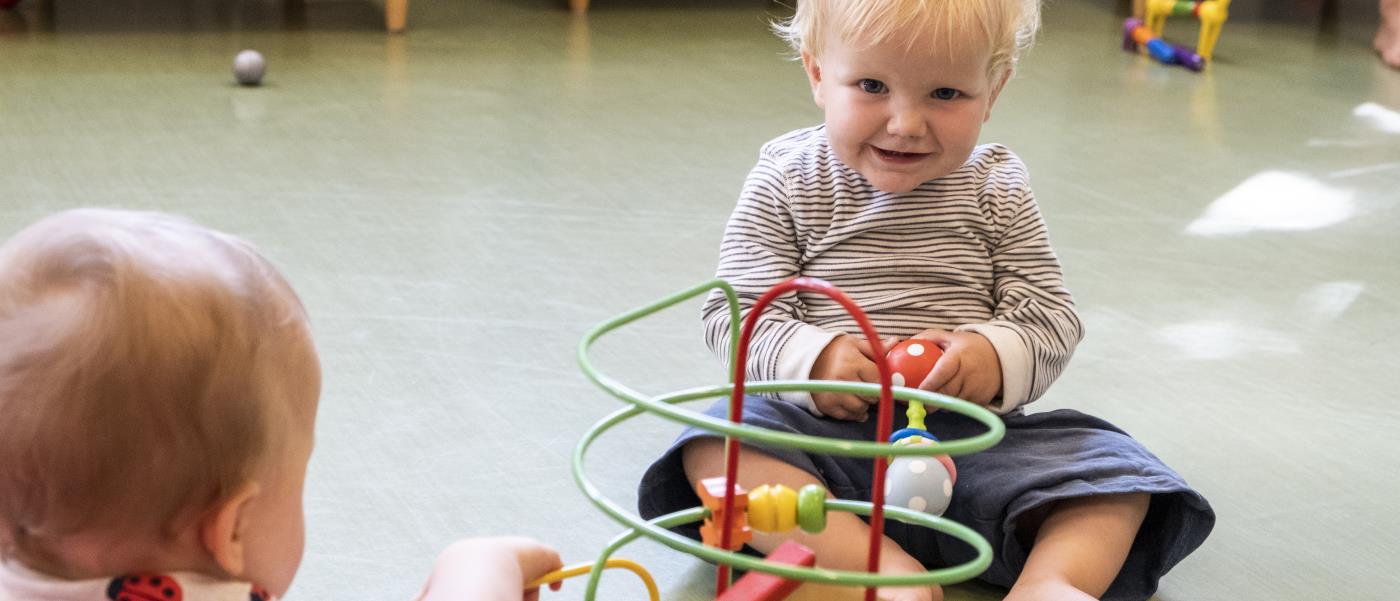 Två bebisar sitter på golvet och leker.