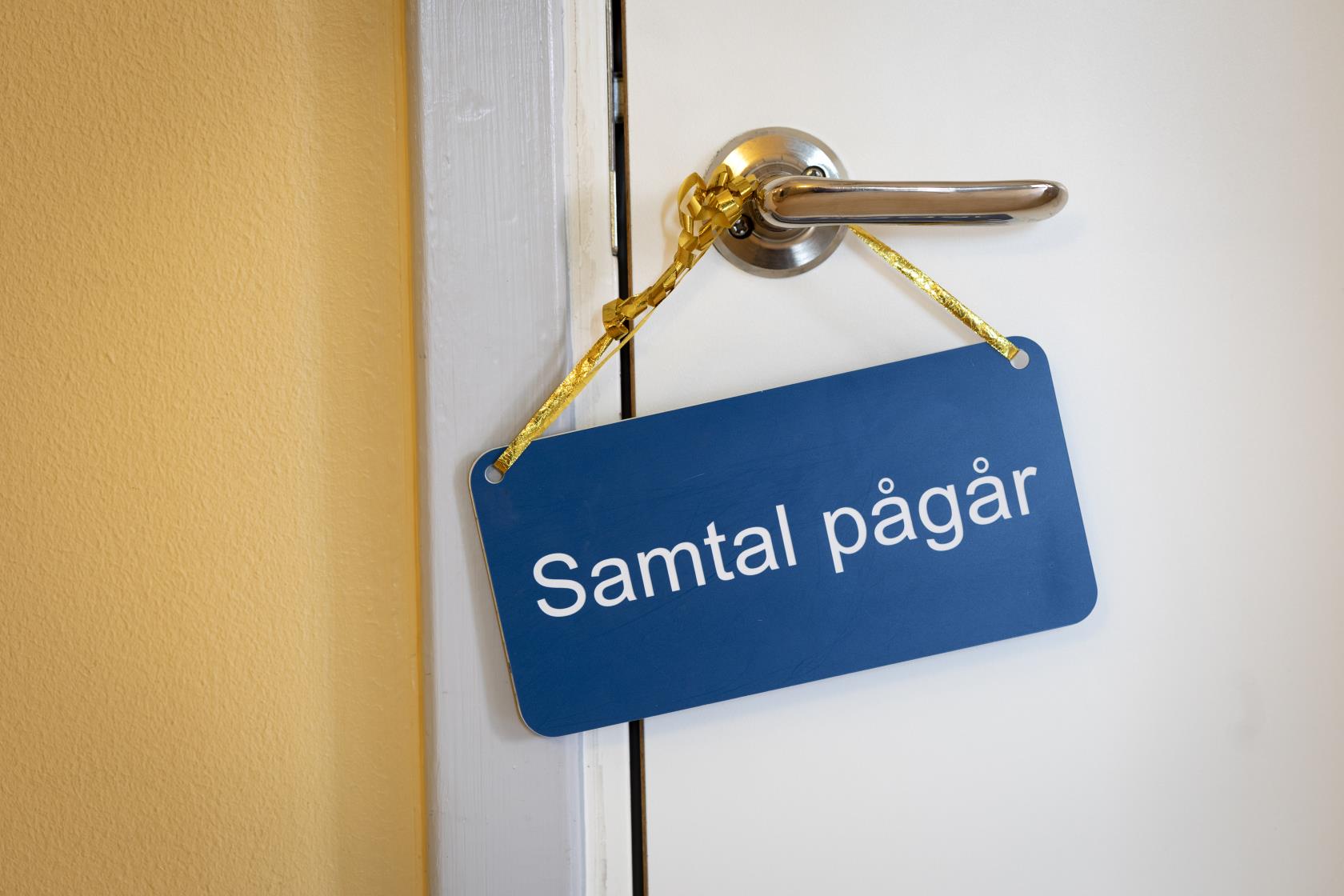 På ett handtag hänger en skylt med texten Samtal pågår.