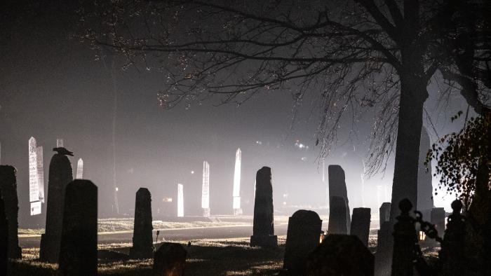 En mörk kyrkogård som lyses upp av en strålkastare.