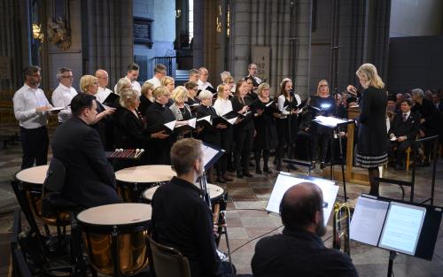 En orkester och en blandad kör framför musik i Uppsala domkyrka under ledning av en kvinnlig dirigent.