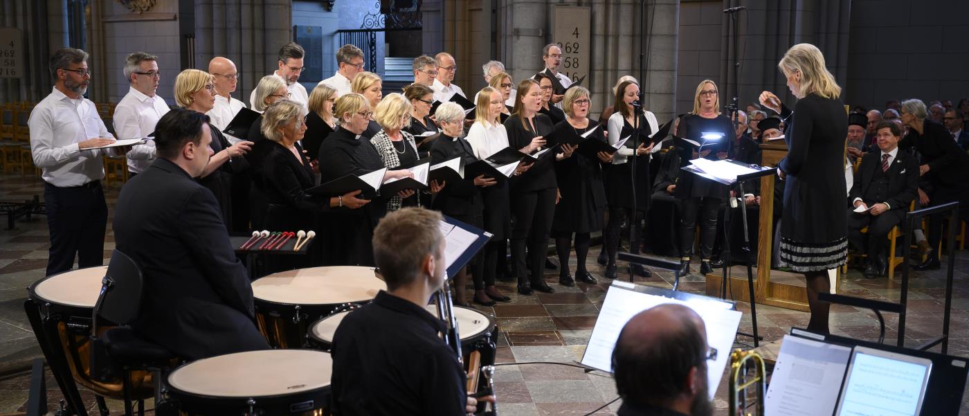 En orkester och en blandad kör framför musik i Uppsala domkyrka under ledning av en kvinnlig dirigent.
