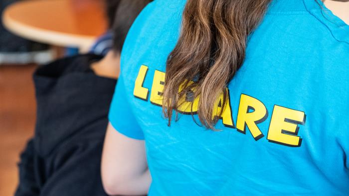 Någon har en blå t-shirt med gula blockbokstäver på ryggen med texten Ledare.