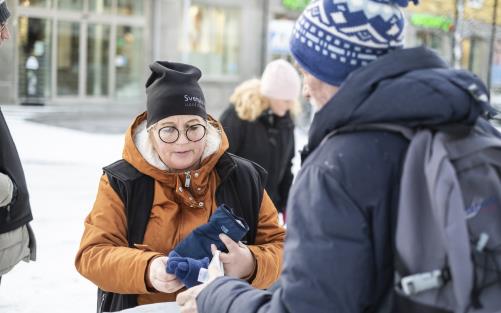 En kvinna delar ut ett par fingervantar till en man.