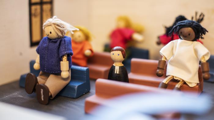 En miniatyrscen med handgjorda dockor som sitter i kyrkbänkar.