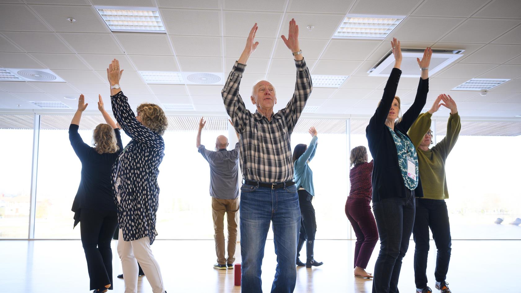 En grupp män och kvinnor dansar i en ring med händerna mot taket.