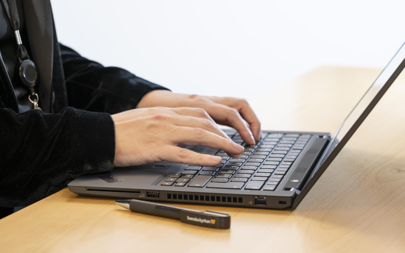 Någon sitter och skriver på sin laptop.