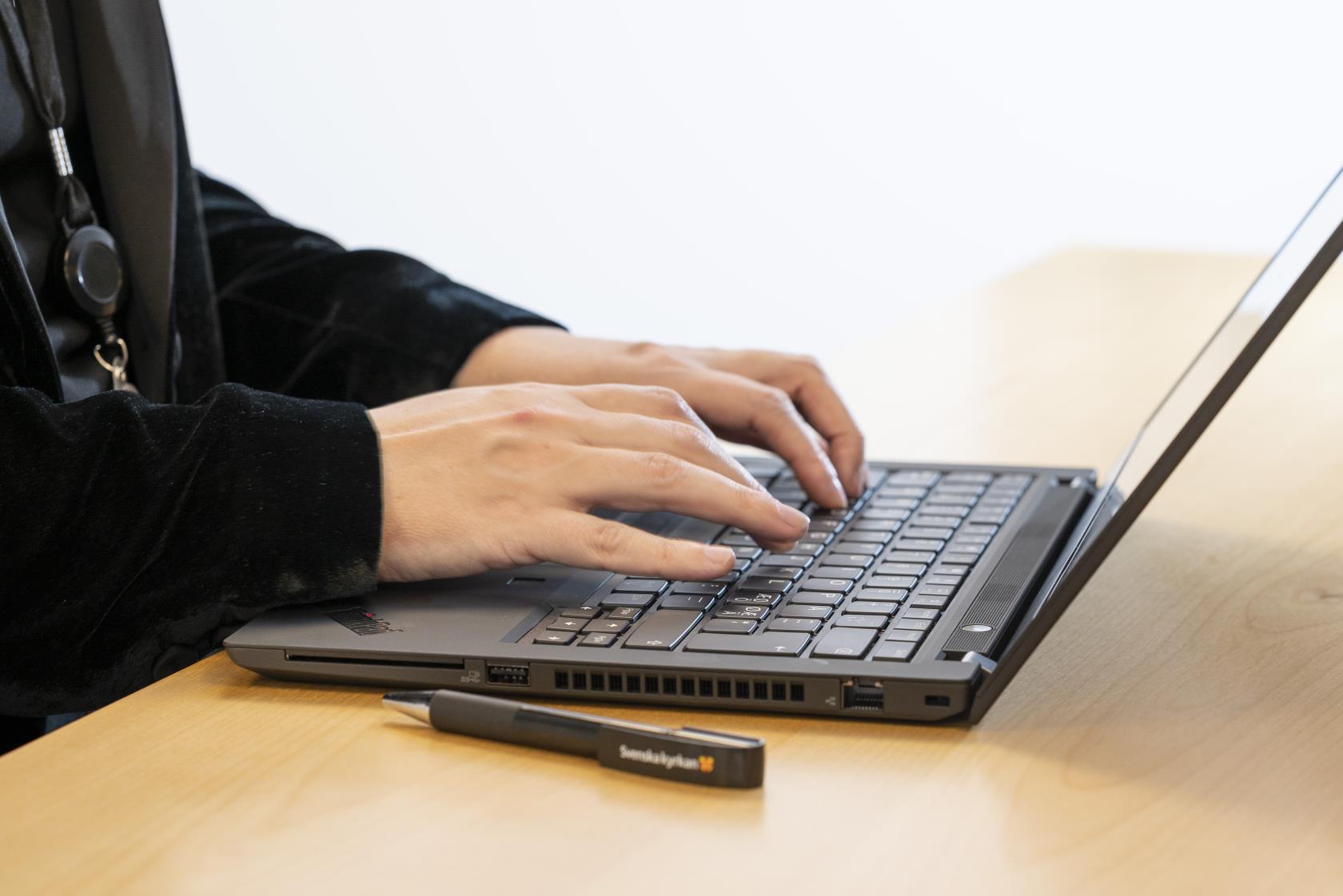 Någon sitter och skriver på sin laptop.