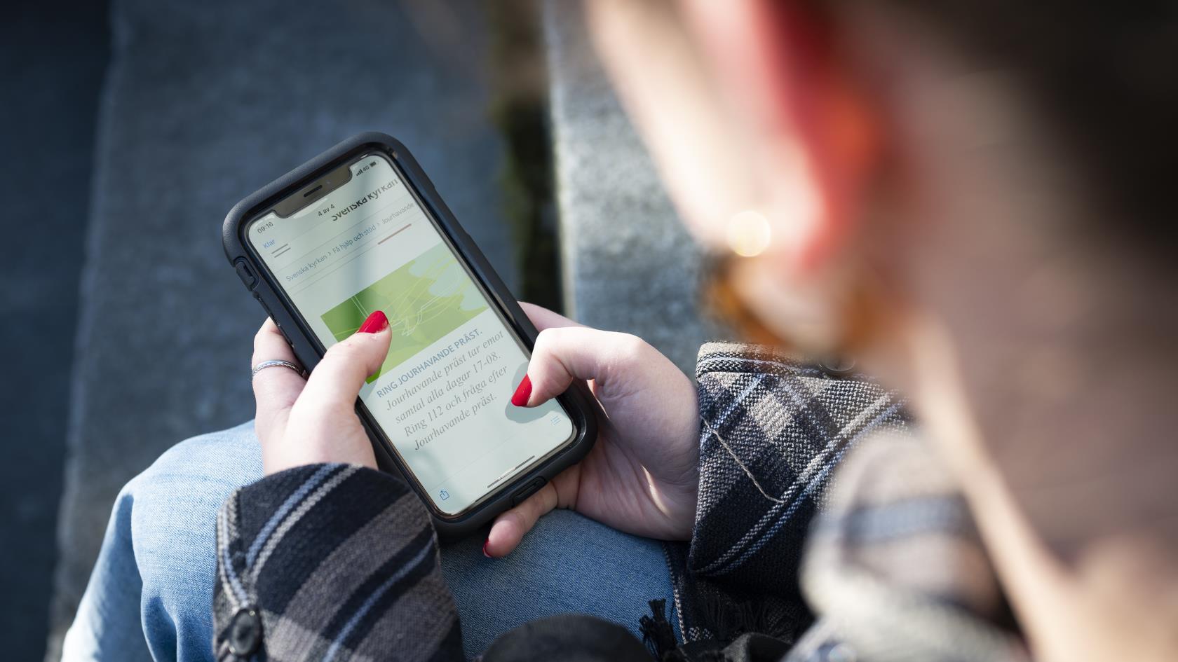 En person sitter och surfar på sin mobiltelefon.