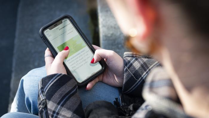 En person sitter och surfar på sin mobiltelefon.