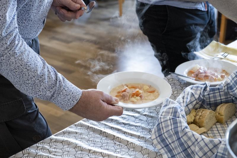 Någon håller en tallrik soppa i handen.