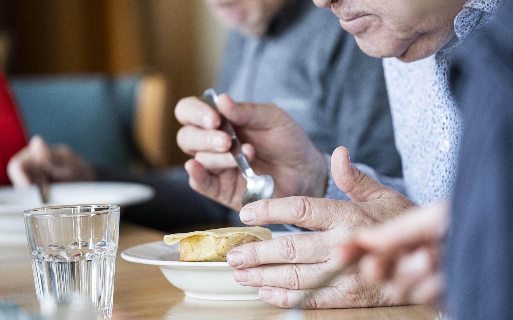 Några personer sitter runt matbordet och äter.