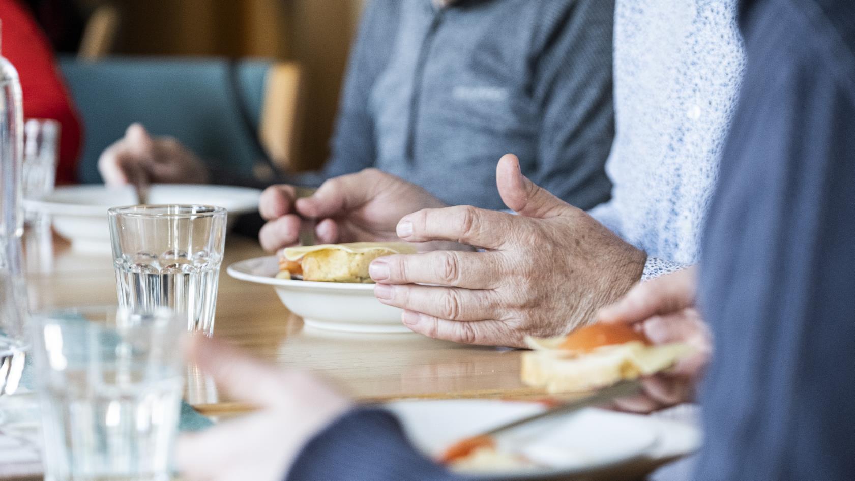 Några personer sitter runt matbordet och äter.