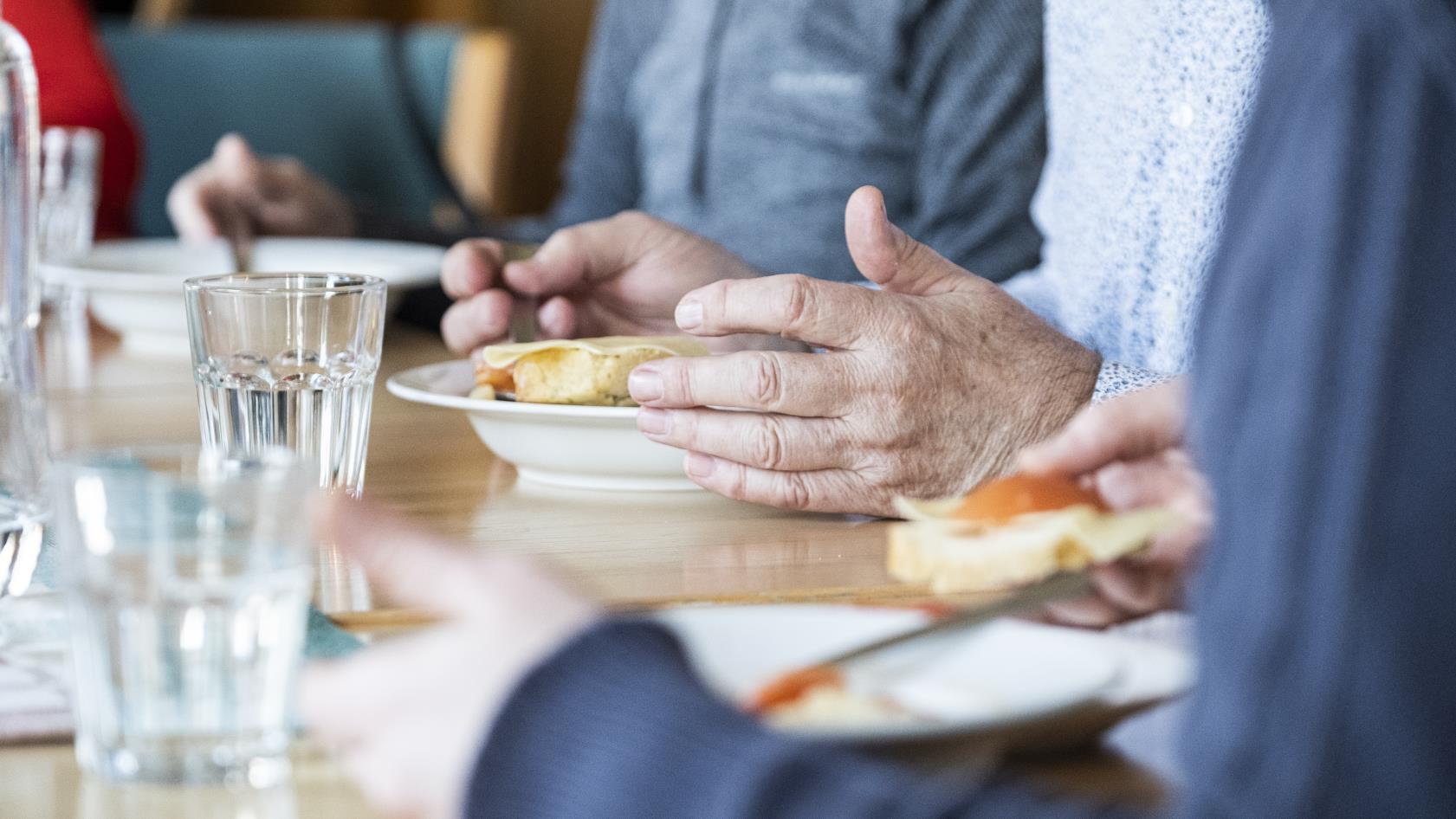 Några personer sitter runt matbordet och äter.