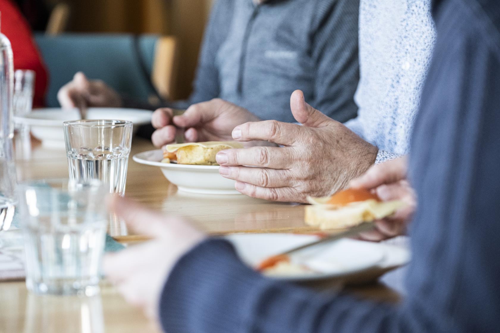 Några personer sitter runt matbordet och äter.