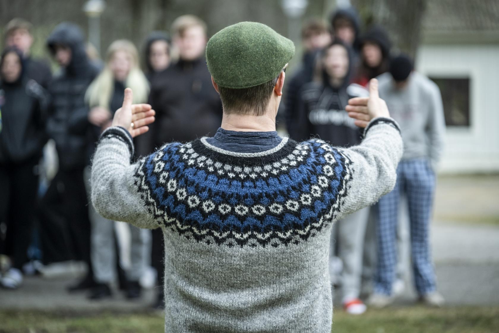 En ledare står och pratar framför en grupp ungdomar.