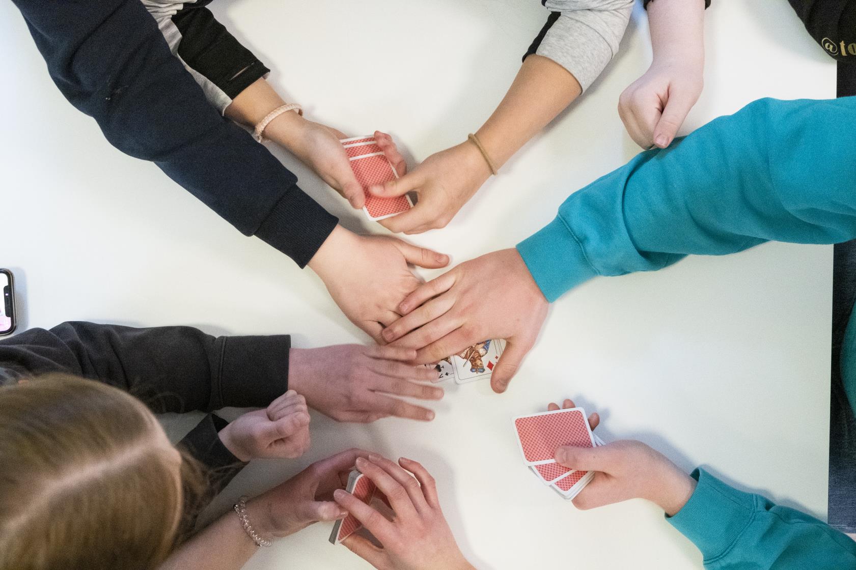 Några ungdomar spelar kort tillsammans.