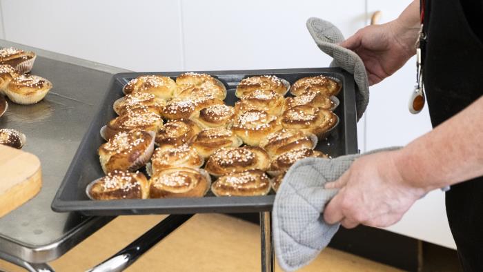 Någon ställer ifrån sig en plåt nybakta kanelbullar.