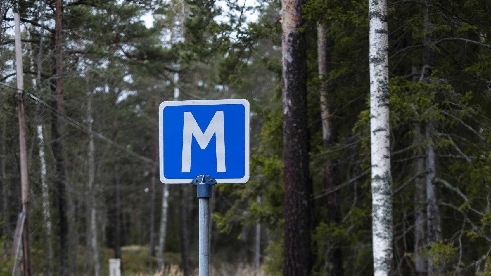 En skylt för mötesplats på en väg i skogen.