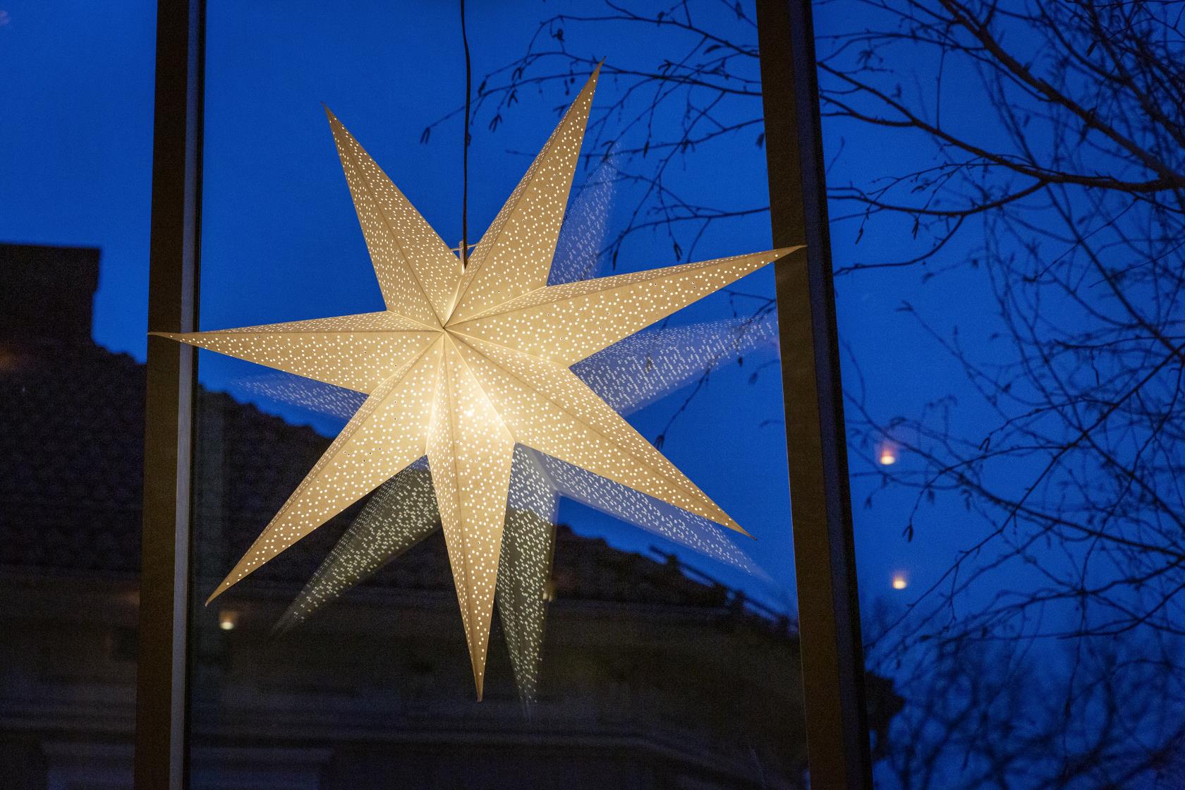 En vit adventsstjärna lyser upp ett fönster.