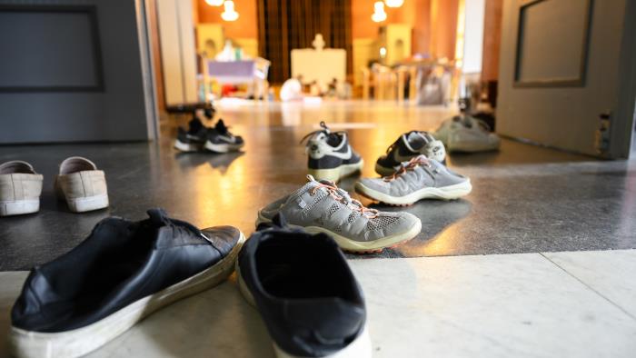 Flera par skor ligger utspridda i en hall.