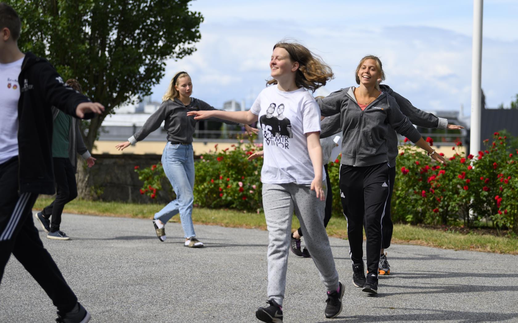 Några glada ungdomar går runt i en ring utomhus.