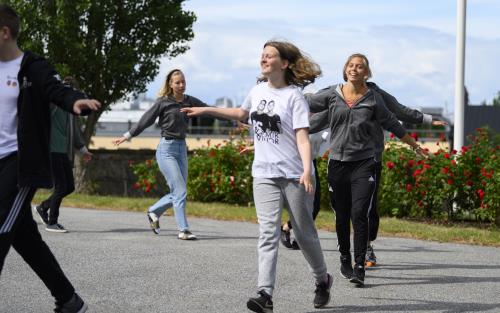 Några glada ungdomar går runt i en ring utomhus.