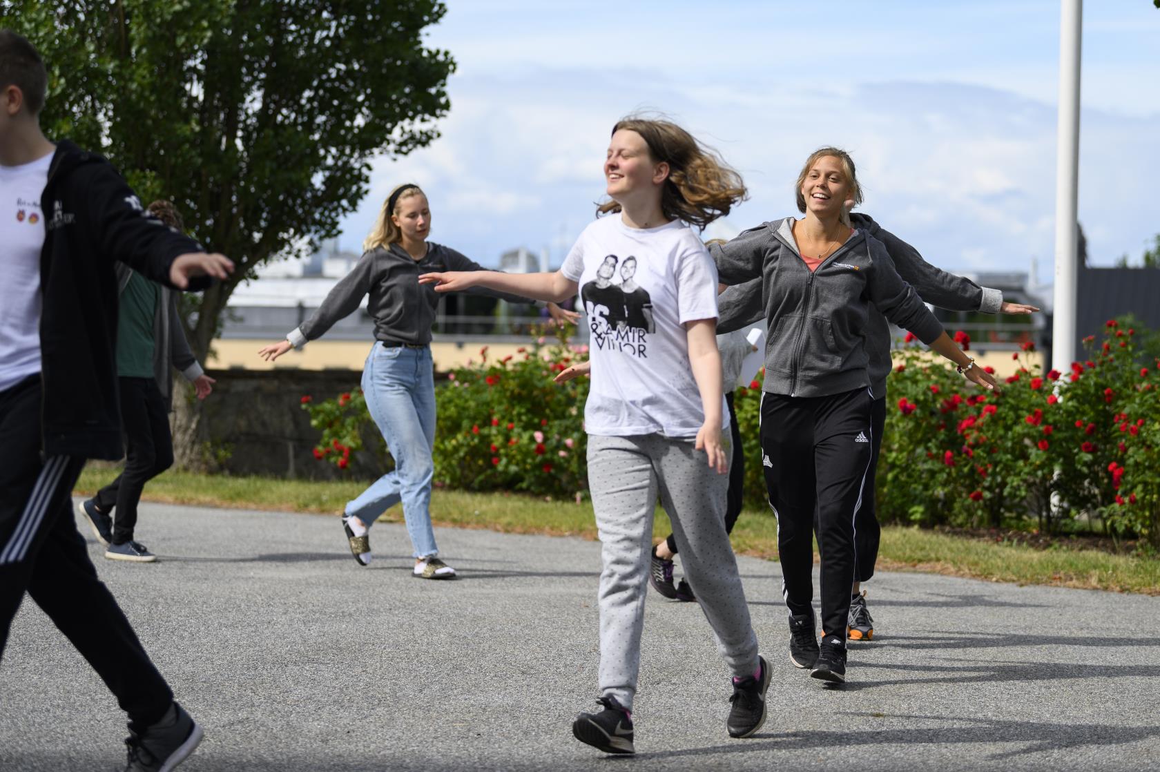 Några glada ungdomar går runt i en ring utomhus.