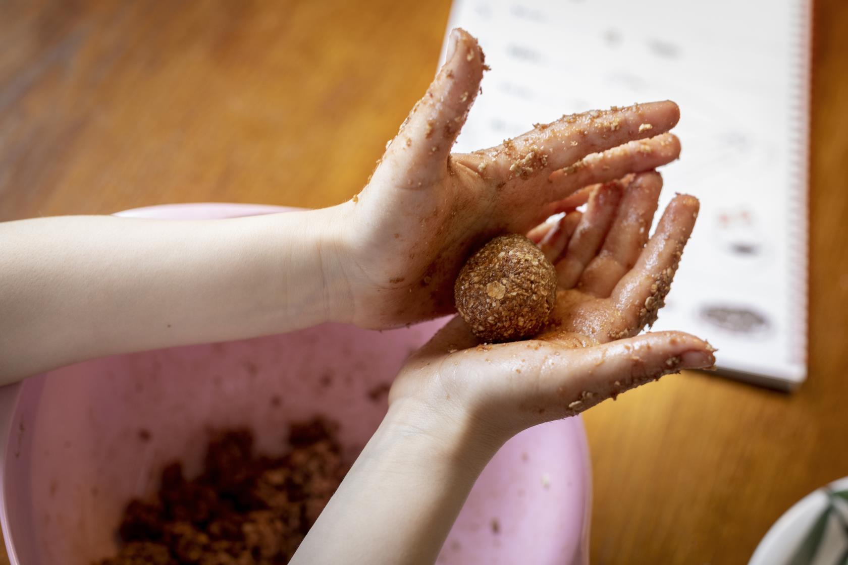 Kladdiga barnhänder rullar en chokladboll.