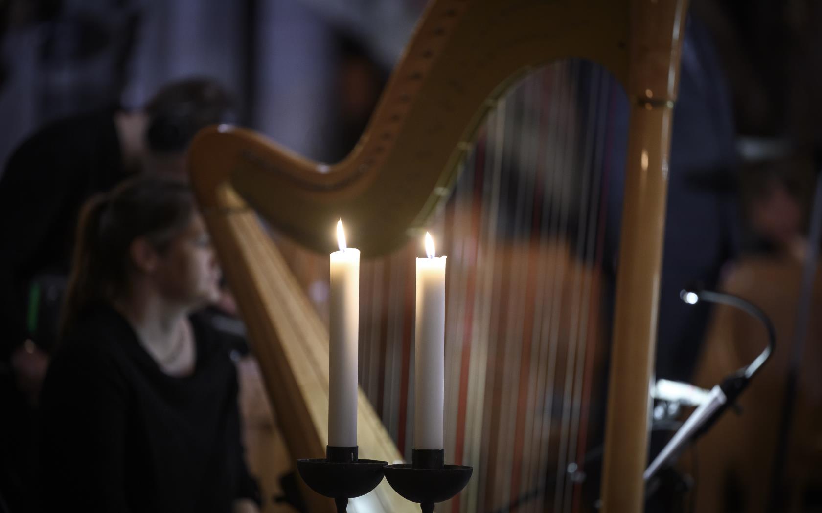 Två tända stearinljus framför en harpa.