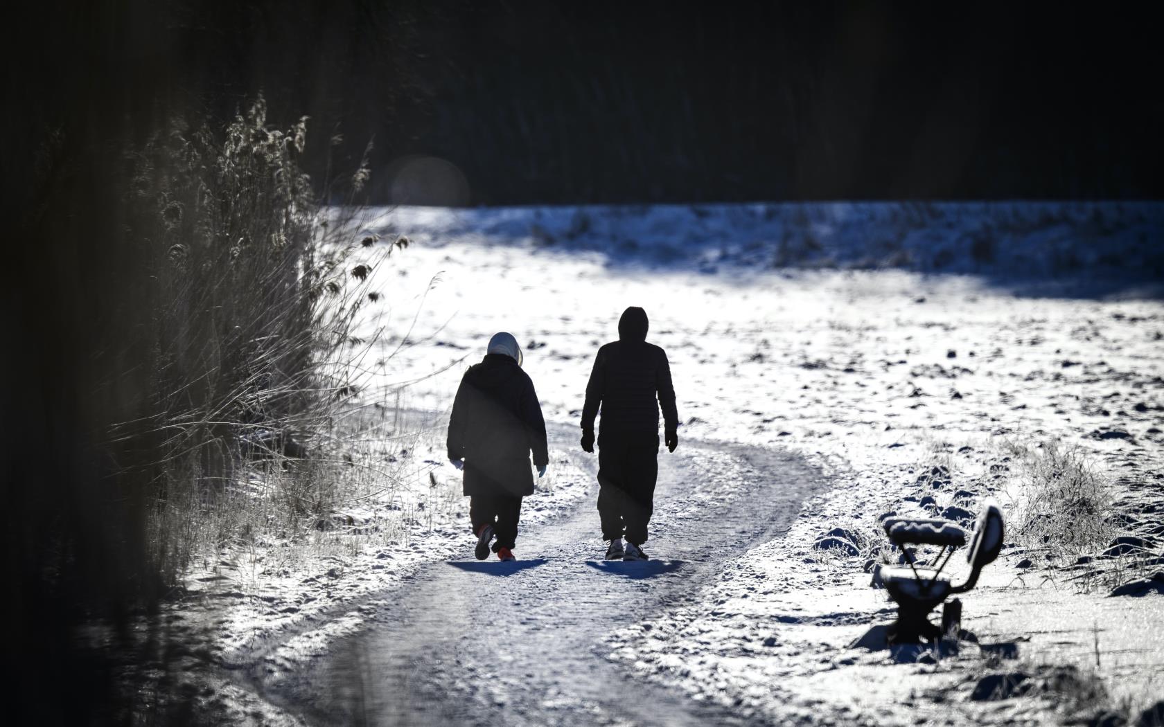 Två personer är ute på långpromenad. Det är vinter och solen skiner.