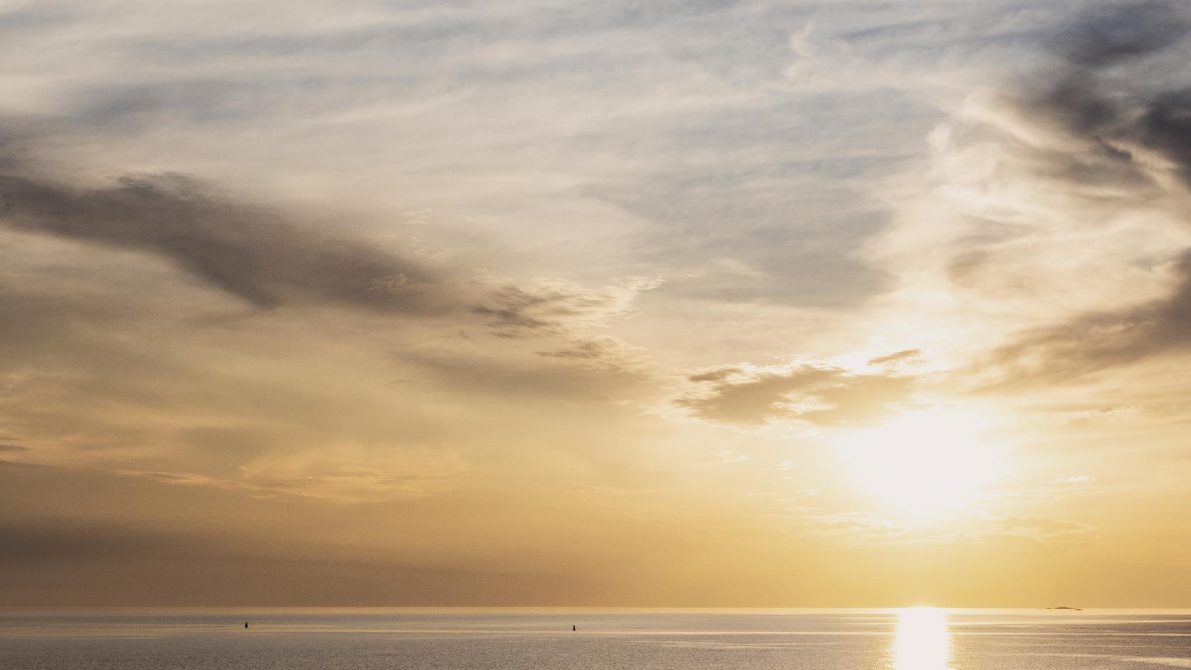 På en klippa vid havet har en grupp personer slagit sig ner för att se på solnedgången.