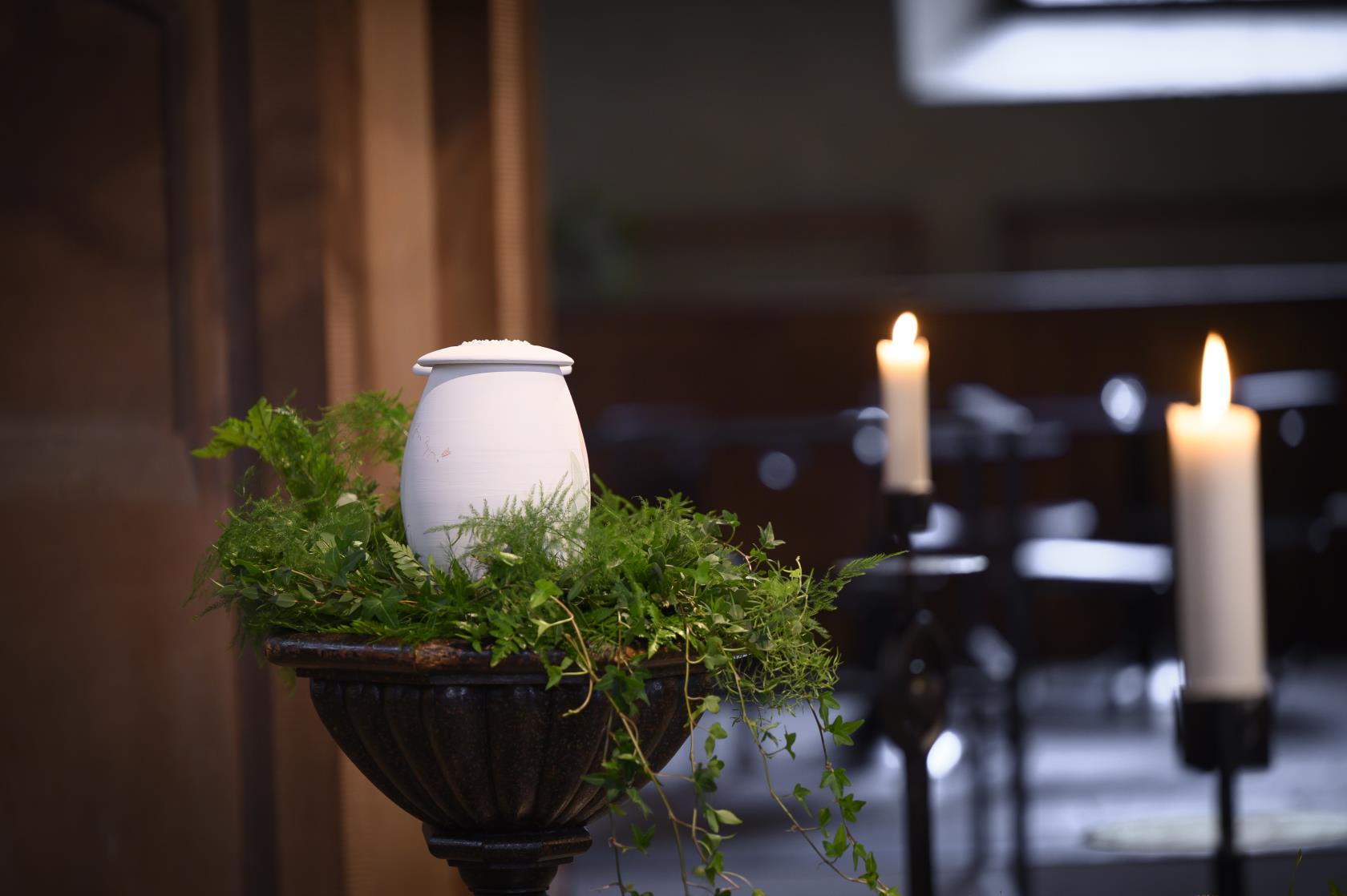 En urna står uppställd bland ormbunksblad i kyrkan.