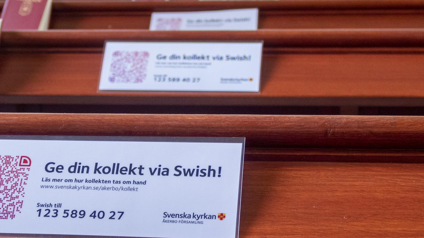 Lappar med texten Ge din kollekt via Swish ligger i kyrkbänkarna.