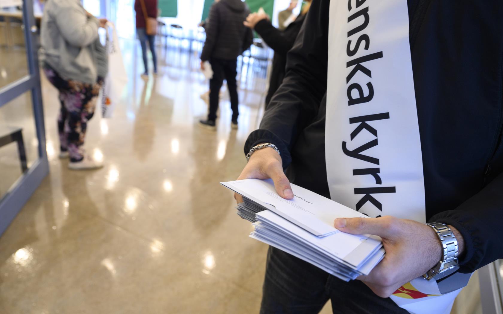 En person från Svenska kyrkan håller i en bunt valkuvert.