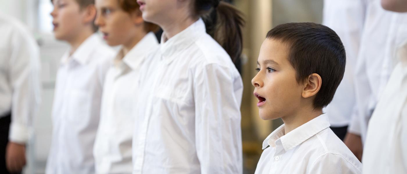 Närbild på medlemmar i en barnkör som sjunger i en kyrka.