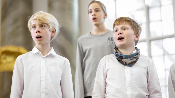 Närbild på medlemmar i en barnkör som sjunger i en kyrka.