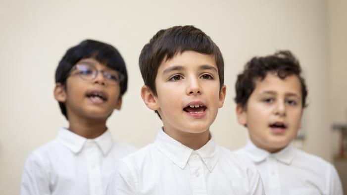 Närbild på medlemmar i en barnkör som sjunger i en kyrka.