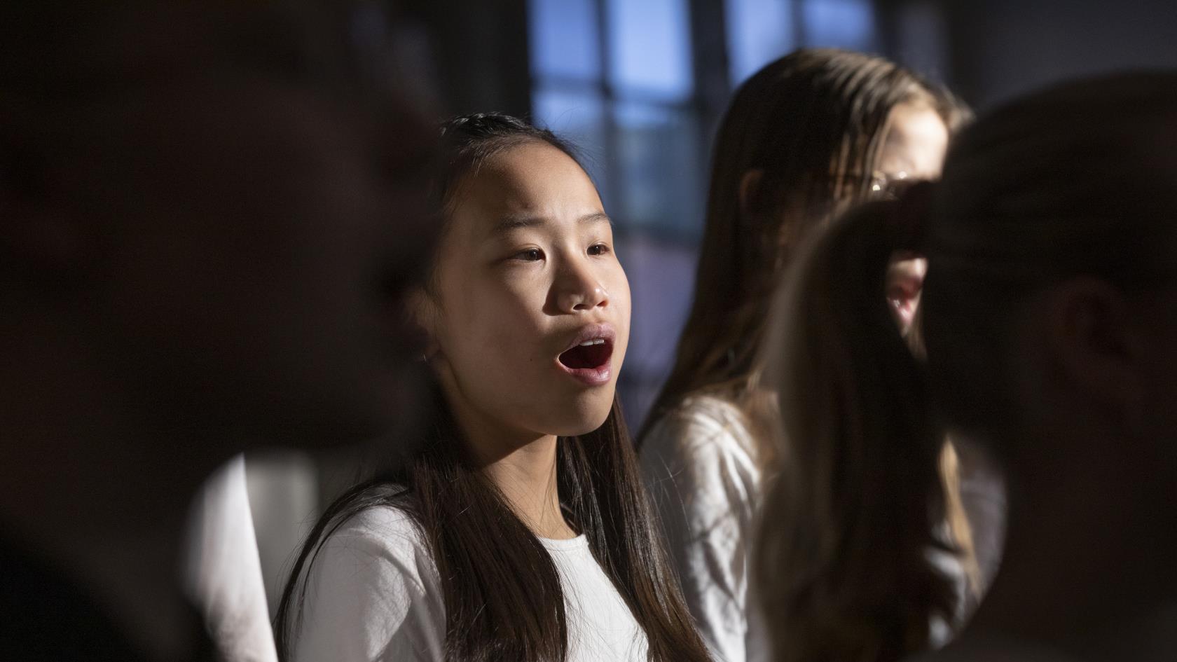 Närbild på medlemmar i en barnkör som sjunger i en kyrka.