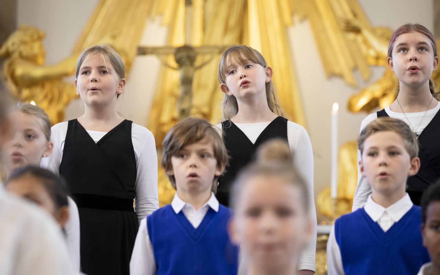 Medlemmar i en barnkör står och sjunger i en kyrka.