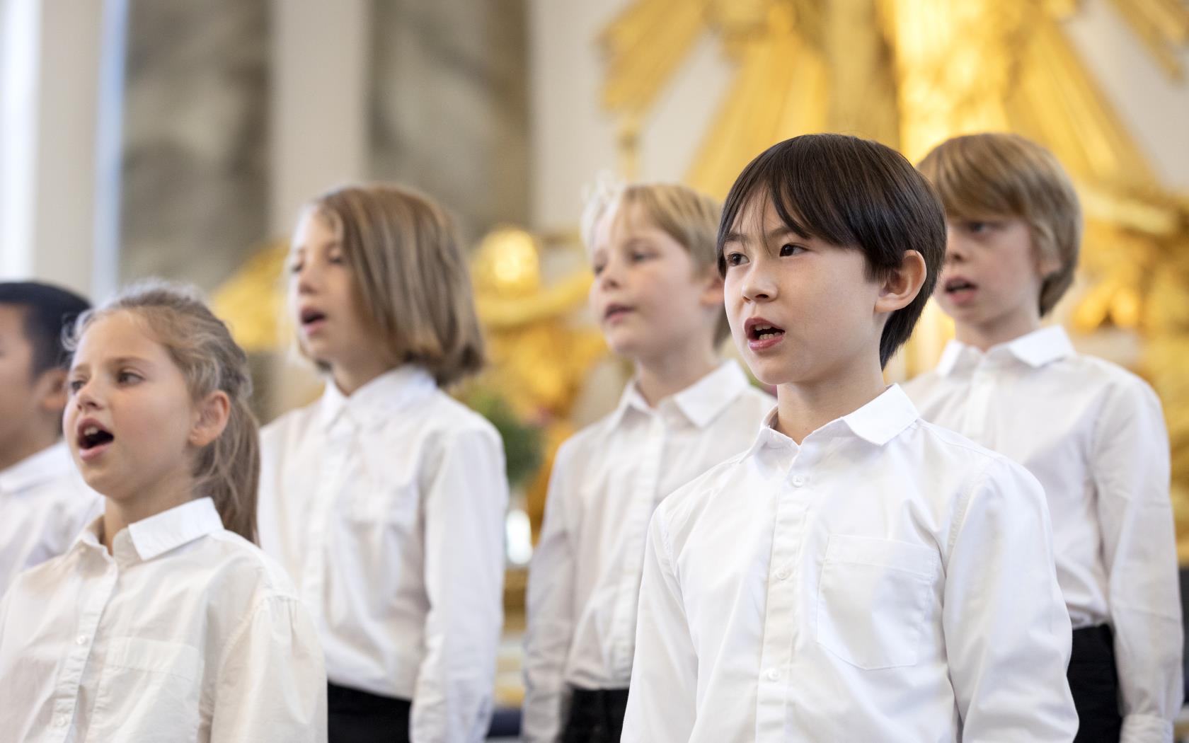 Medlemmar i en barnkör står och sjunger i en kyrka.