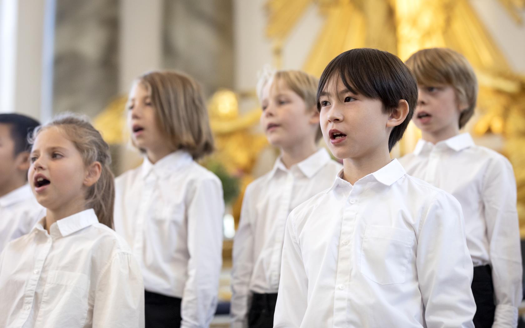 Medlemmar i en barnkör står och sjunger i en kyrka.