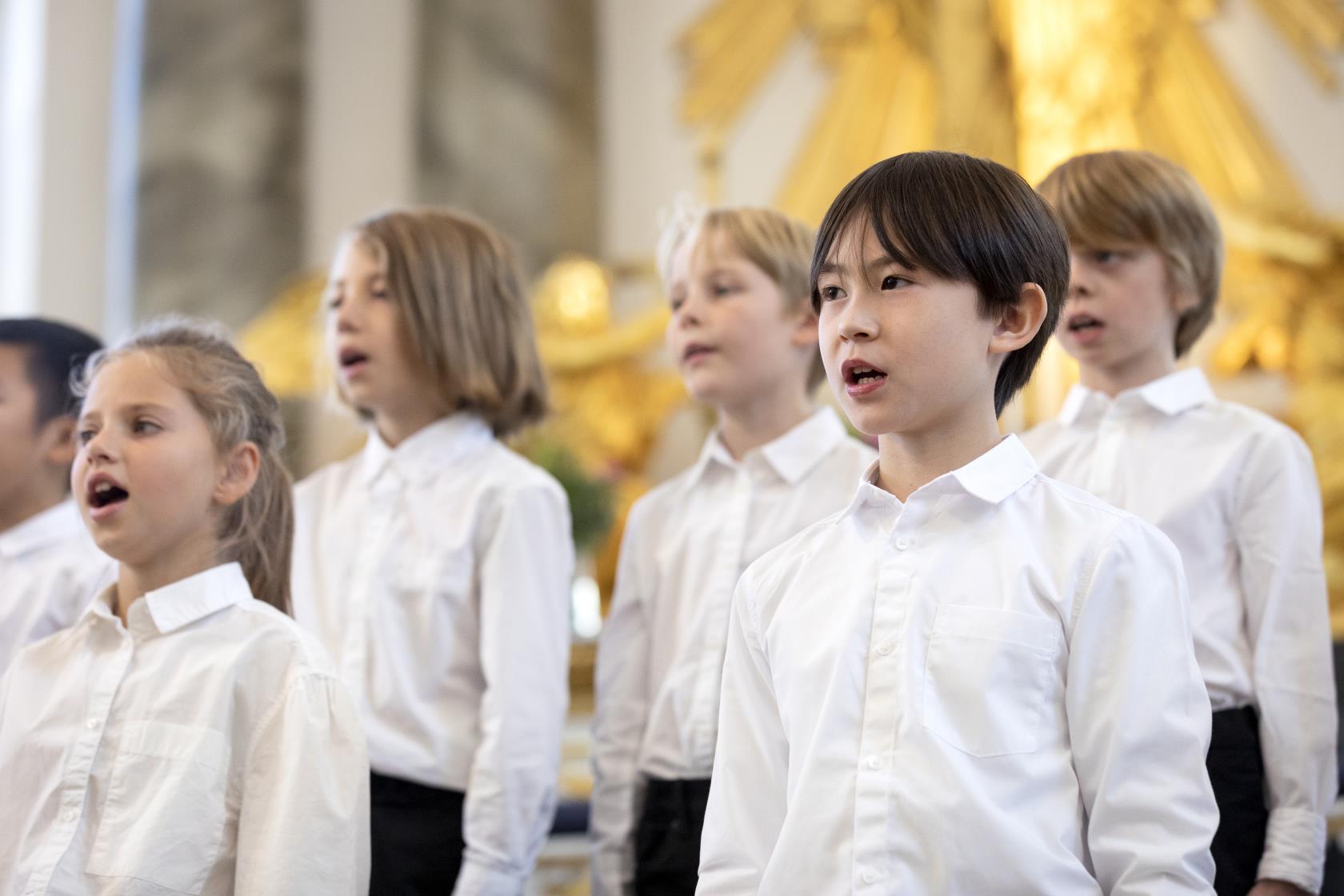 Medlemmar i en barnkör står och sjunger i en kyrka.