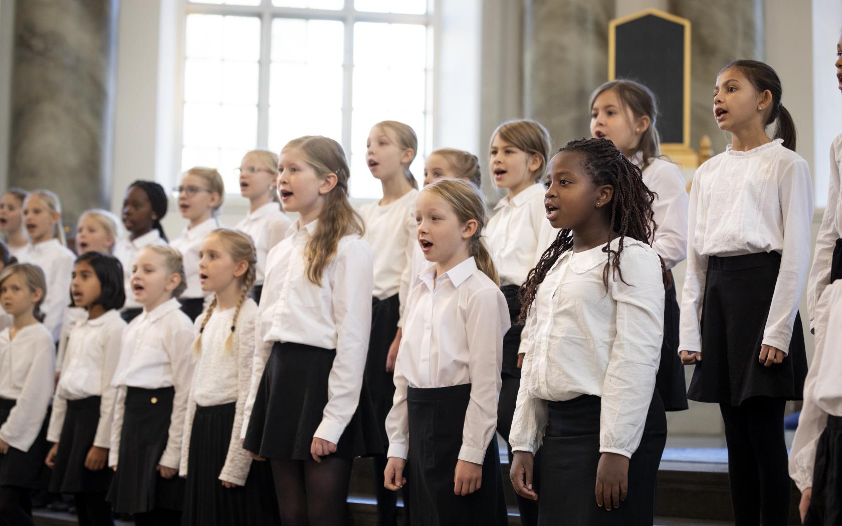 Medlemmar i en barnkör står och sjunger i en kyrka.