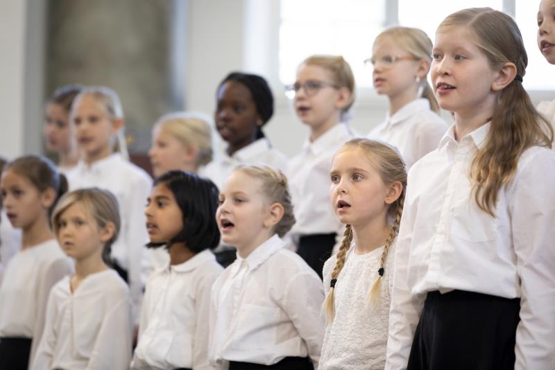 Medlemmar i en barnkör står och sjunger i en kyrka.