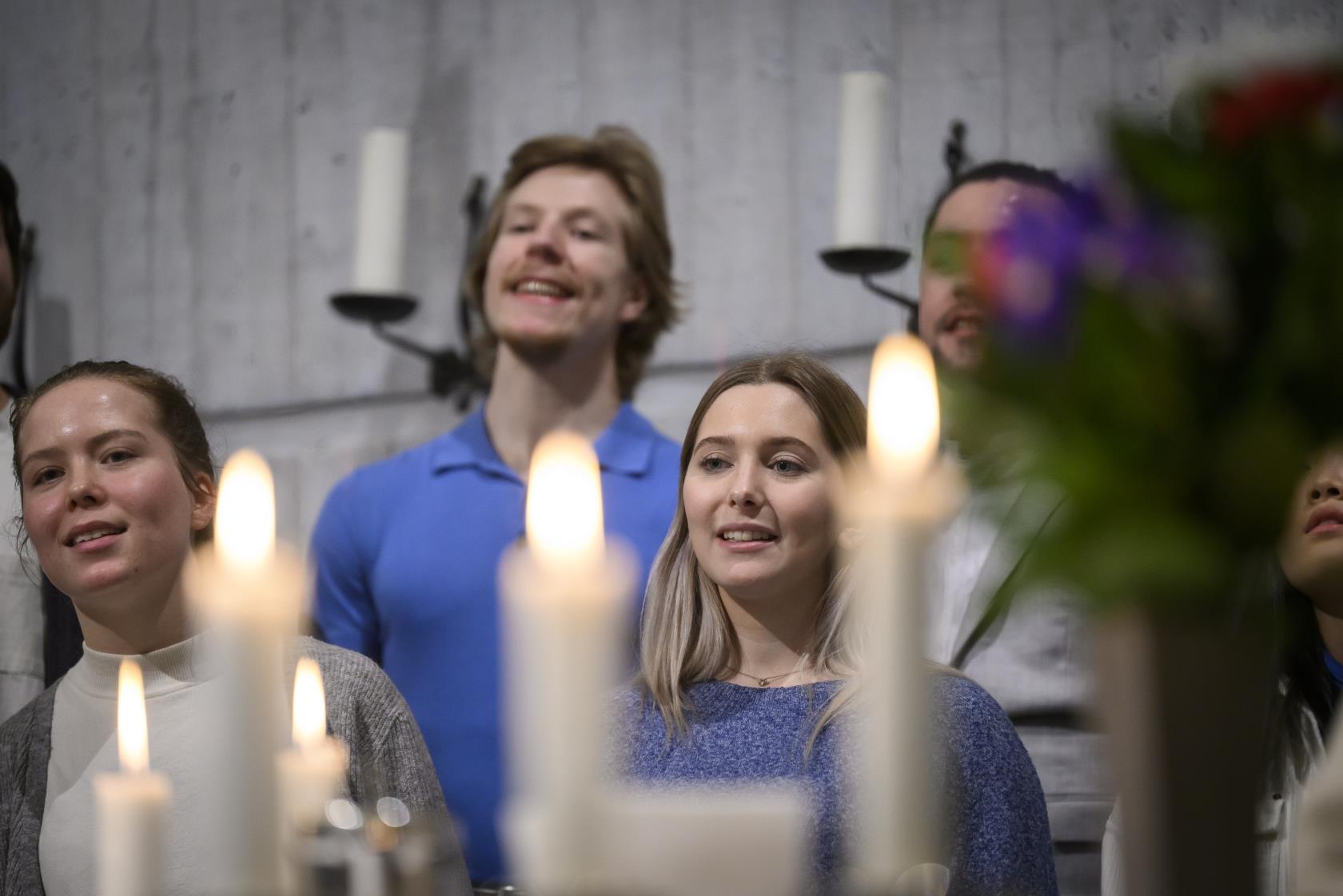 Några medlemmar ur en blandad ungdomskör som sjunger.