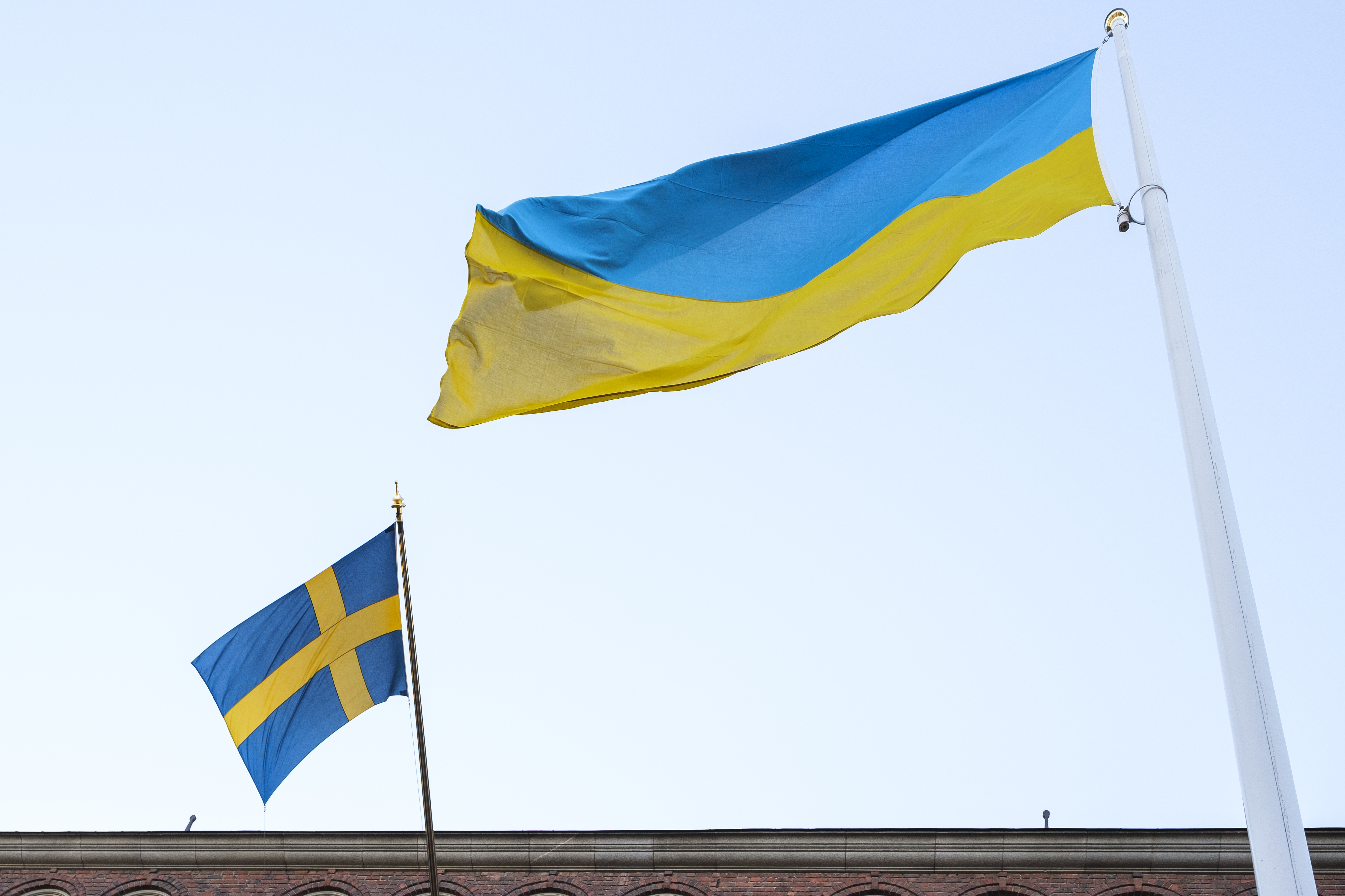 Svenska flaggan och Ukrainska flaggan vajar i varsin flaggstång.