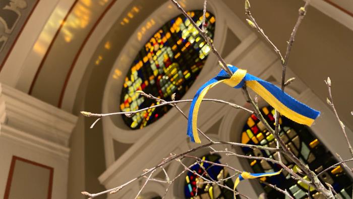 I en kyrka står ett vårris med knutna band i gult och blått.